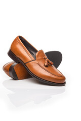 Footwear Concepts. Closeup View of Pair of Traditional Formal Stylish Light Brown Polished Calf Leather Tassel Loafer Shoes Placed on One Another On Pure White.