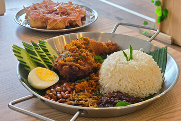 Nasi Lemak with Fried Chicken and Condiments on Wooden Table