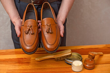 Footwear Concepts. Hands of Professional Male Shoes Cleaner with Cleaning Shoe Wax, Cream and Brushes For Tan Calf Leather Tassel Loafers Shoes While Working