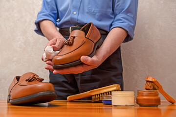 Hands of Professional Male Shoes Cleaner with Cleaning Shoe Wax, Cream and Brushes For Tan Calf Leather Tassel Loafers Shoes While Working