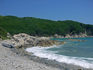 Rocky coast with turquoise water and inflatable boat on the shore