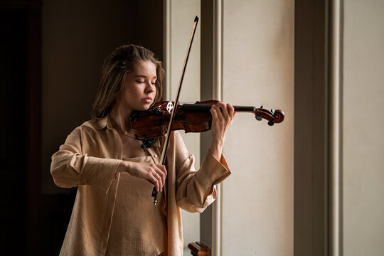 woman plays the violin with a bow in a music class.