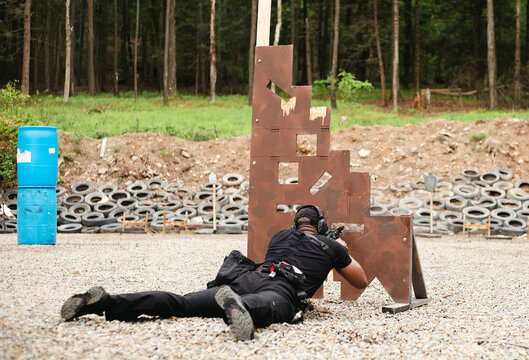 A man in a recumbent position shoots through a barrier into a target