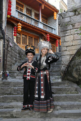 Tourist people, woman with child, kid in miao traditional national dress in Furong Ancient Town. Furong town (Chinese: 芙蓉) in Yongshun County, Xiangxi Prefecture, Hunan. Beautiful girl in miao hat