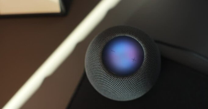 HomePod Mini speaker with assistant to play music, static on desk. Concept of a smart home.