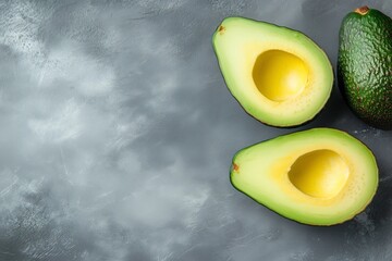 Fresh avocado halves on gray concrete background, top view

