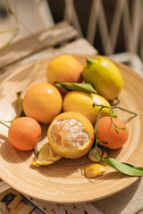 Fresh juicy oranges, tangerines and lemons on a beautiful wooden platter on a sunny terrace.