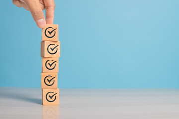 Check mark icon on wooden cube symbolizing goal achievement, verification, or progress tracking. Clean background with space for text.