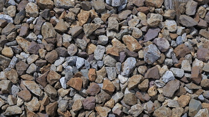 Close-up, high-angle shot reveals a dense, textured field of railway ballast rocks featuring diverse, irregular shapes, are tightly packed, forming a stable bed for railway tracks