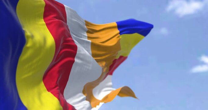 The international Buddhist flag waving against a blue sky.