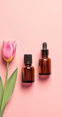 Two amber glass bottles with droppers sit atop a pink surface, beside a pink tulip