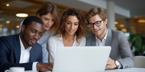 Diverse group of young professionals collaborating on laptop in modern office setting