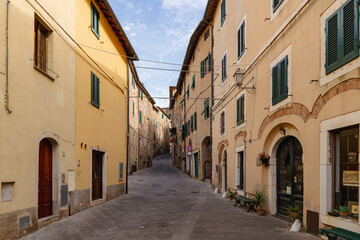 Narrow stone alley in Campiglia Marittima, old village in Tuscany, Italy with rustic buildings and colorful details.