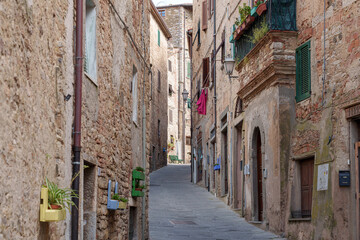 Narrow stone alley in Campiglia Marittima, old village in Tuscany, Italy with rustic buildings and colorful details.
