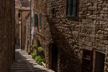 Narrow stone alley in Campiglia Marittima, old village in Tuscany, Italy with rustic buildings and colorful details.