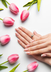 Woman showing french manicure near pink tulips on white background