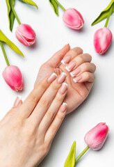 Woman showing french manicure near pink tulips on white background