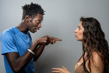 Man accusingly pointing his finger at a woman during a heated argument, diverse couple fighting.