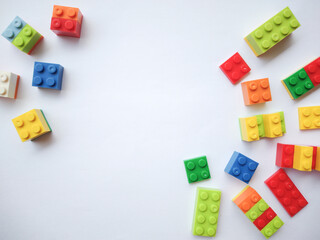 Obraz premium Colorful plastic bricks on white background. Educational toys for kids mockup, top view. Concept of education, children's creativity. Copy space.