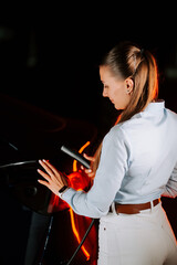 Woman charges electric vehicle in modern underground parking facility at night