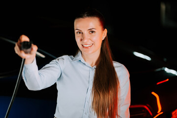 Woman charging electric car in underground parking lot during evening hours