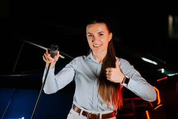 Woman charging electric car in underground parking lot at night