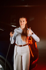 Woman charging electric vehicle in underground parking garage during evening hours