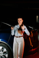 Woman charges electric car in underground parking lot while giving thumbs up