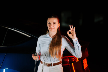 Woman charges electric car in underground parking lot at night