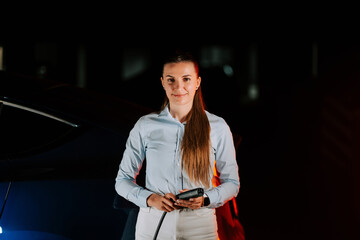 Woman charges electric car in underground parking lot during nighttime