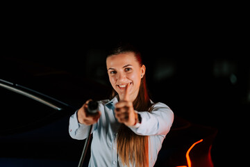 Woman enjoys electric car charging in underground parking lot at night