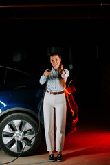 Woman charging electric car in underground parking lot with positive attitude and modern attire