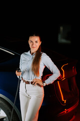 Woman charging electric car in underground parking lot during evening hours
