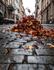Moody autumn scene on a cobblestone street. A pile of colorful leaves cascades downwards. Perfect for seasonal promotions, urban themes, or transitional periods.