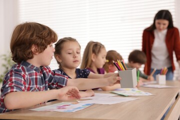 Fototapeta premium Woman teaching kids to draw at painting lesson indoors, selective focus