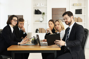 Coworkers working together at wooden table in office