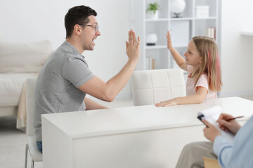 Fototapeta premium Father and daughter having consultation with psychologist in office, selective focus
