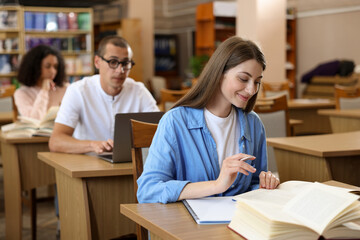 People studying at desks in public library, selective focus