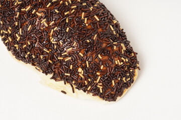 Milk bread with a soft white interior, topped generously with chocolate sprinkles and a touch of white topping. Photographed against a clean white background.