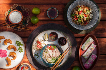 Authentic Vietnamese cuisine including pho bo, spring rolls with shrimp and noodles, fried shrimp, chicken noodles, rice, and pickled vegetables. Flat lays and styled food shots