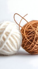 White and brown yarn balls on white background, close-up, crafting