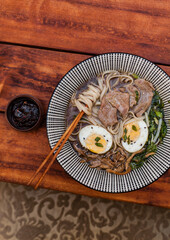 Japanese ramen soup with rice noodles, mushrooms, hard-boiled egg, and fresh toppings. Styled flat...