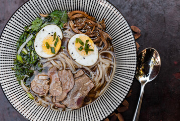 Japanese ramen soup with rice noodles, mushrooms, hard-boiled egg, and fresh toppings. Styled flat...