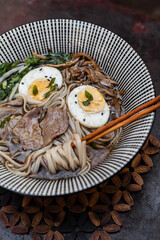 Japanese ramen soup with rice noodles, mushrooms, hard-boiled egg, and fresh toppings. Styled flat lay and close-up food photography with chopsticks