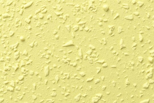 Yellow surface with bumpy grainy texture speckled with raised shapes