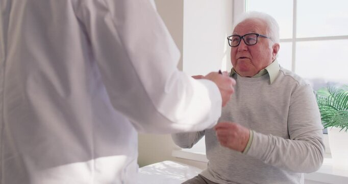 Caring doctor talking to his elderly male patient during medical examination. Patient appears concerned as he expresses health complaints, while doctor attentively listens and takes notes on clipboard