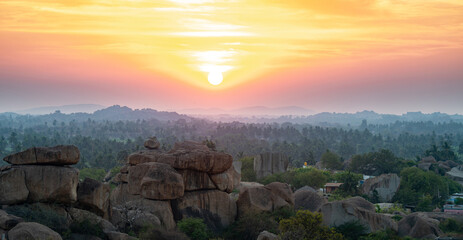 Sunset view from Hemakuta Hill in Hampi, India, boulder landscape with tropical trees, South India, Karnataka, travel destination