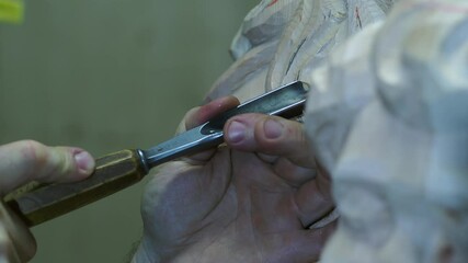 Macro slow motion of Experienced woodworker carving intricate details on religious statue, demonstrating traditional craftsmanship with precision and artistic skill