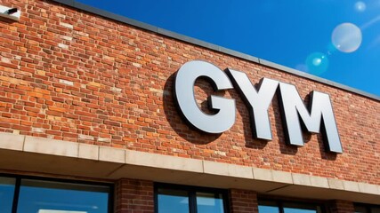 Gym building with sign on brick exterior under clear blue sky  