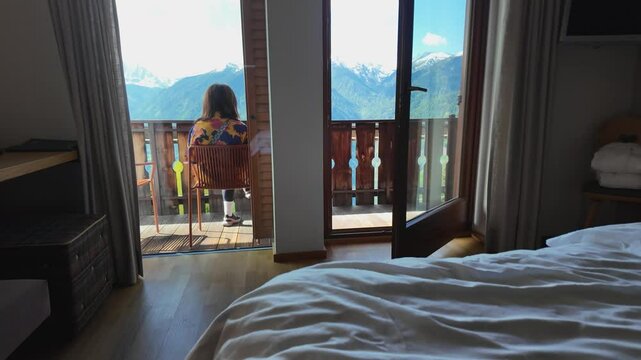 A slow-motion video of a girl admiring the morning view from an accommodation in the Italian Dolomites, with mountain peaks